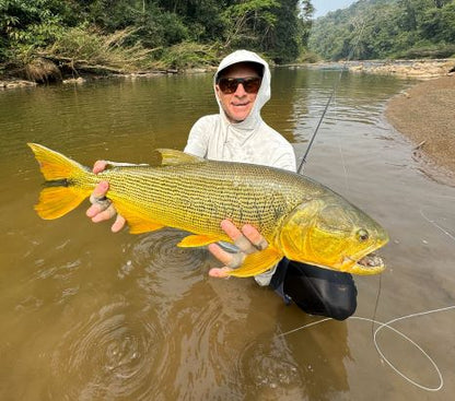Angler holding a golden dirado caught on the Blackened fly