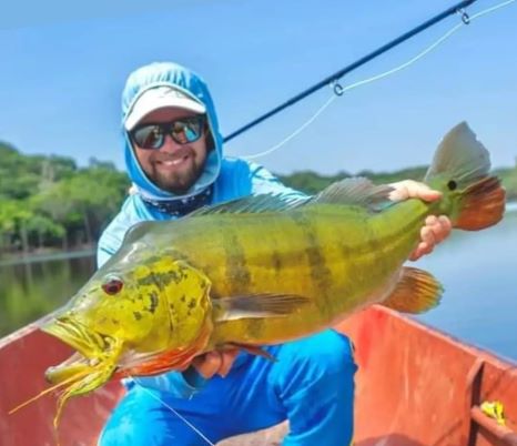 Angler holding a large peacock bass caught on the Fire Tiger Fly