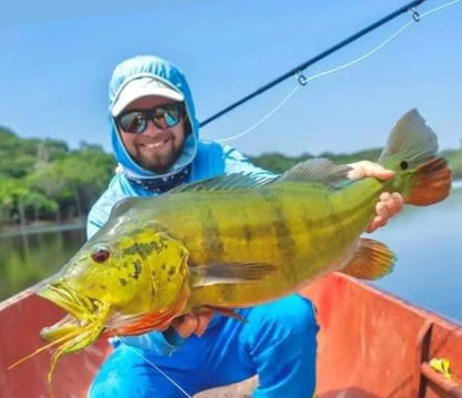 Angler holding a large peacock bass caught on the Fire Tiger Fly