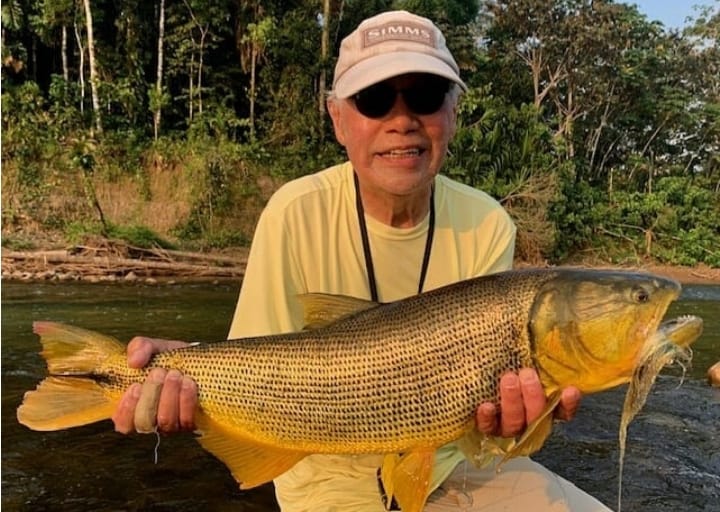 Smiling angler with a golden dorado, caught on the Gray Sabalo fly