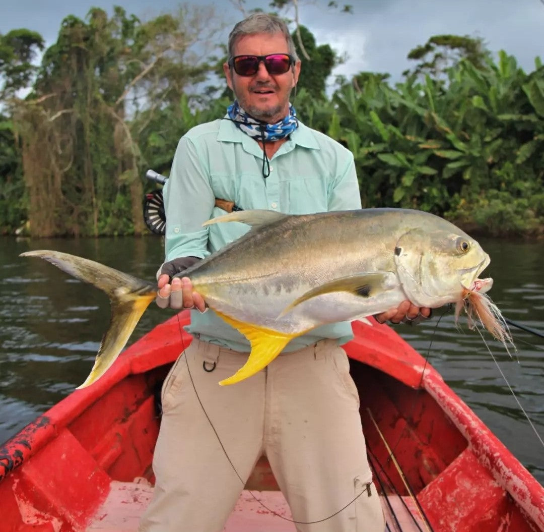 Angler with a jack crevalle caught on the Mullet fly on a red boat