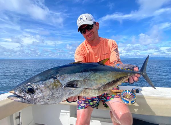 Angler holding a yellow fin tuna caught on the Olive/White fly