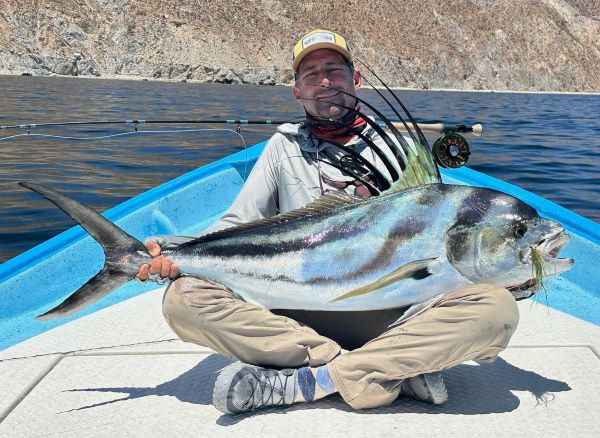 Smiling angler holding a large roosterfish, caught on the Olive/White fly