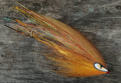 Arenca hand-tied Payara Dragon Fly in orange and amber with a white eye on a weathered wooden background