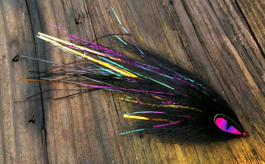 Black hand-tied Payara Dragon Fly with holographic flash and a pink eye on a rustic wood background