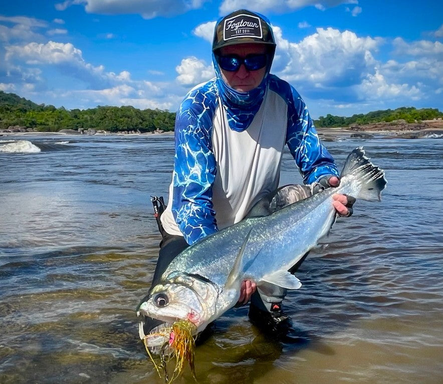 Angler kneeling at the water's edge holding a nice payara caught on the Payara Dragon Fly Figer Tiger