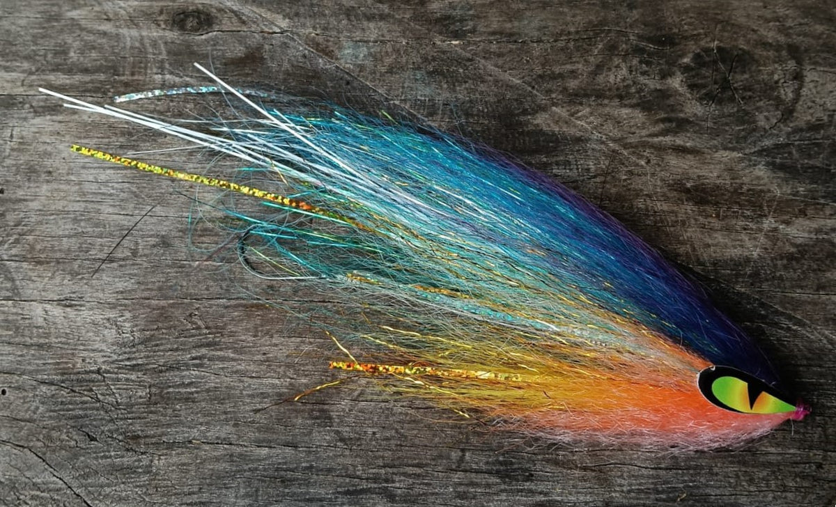 Sardinata hand-tied Payara Dragon Fly in teal blue, orange and pink with a green eye on a dark weathered wood background