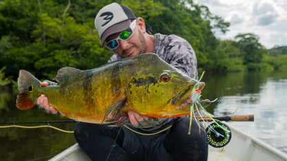 Orinoco Flies founder holding a peacock bass caught on one of his green poppers.