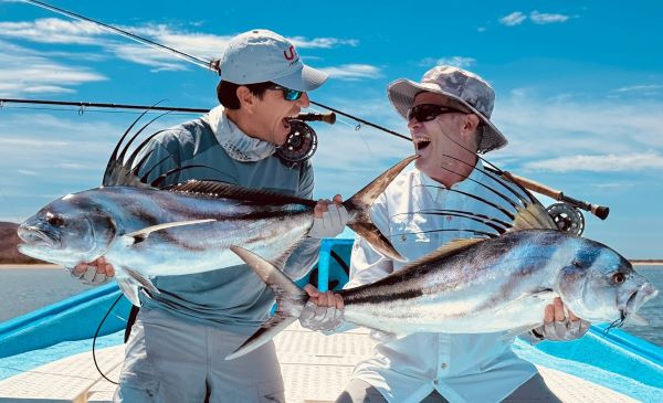 Two happy anglers, each holding a nice rooster fish caught on a Black Tail Bocon Fly