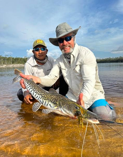Angler and his guide holding a shovel nose catfish caught on the Small Peacock Bass Fly
