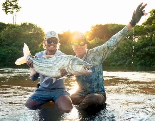 Two anglers celebrating with a tiger fish caught on the Small Peacock Bass Fly
