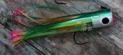 Green hand-tied popper fly with a silver head, black eye and green, orange and pink tail on weathered wood