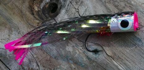 Original popper fly with a silver head, black eye and holographic body with a hot pink tail on weathered wood.
